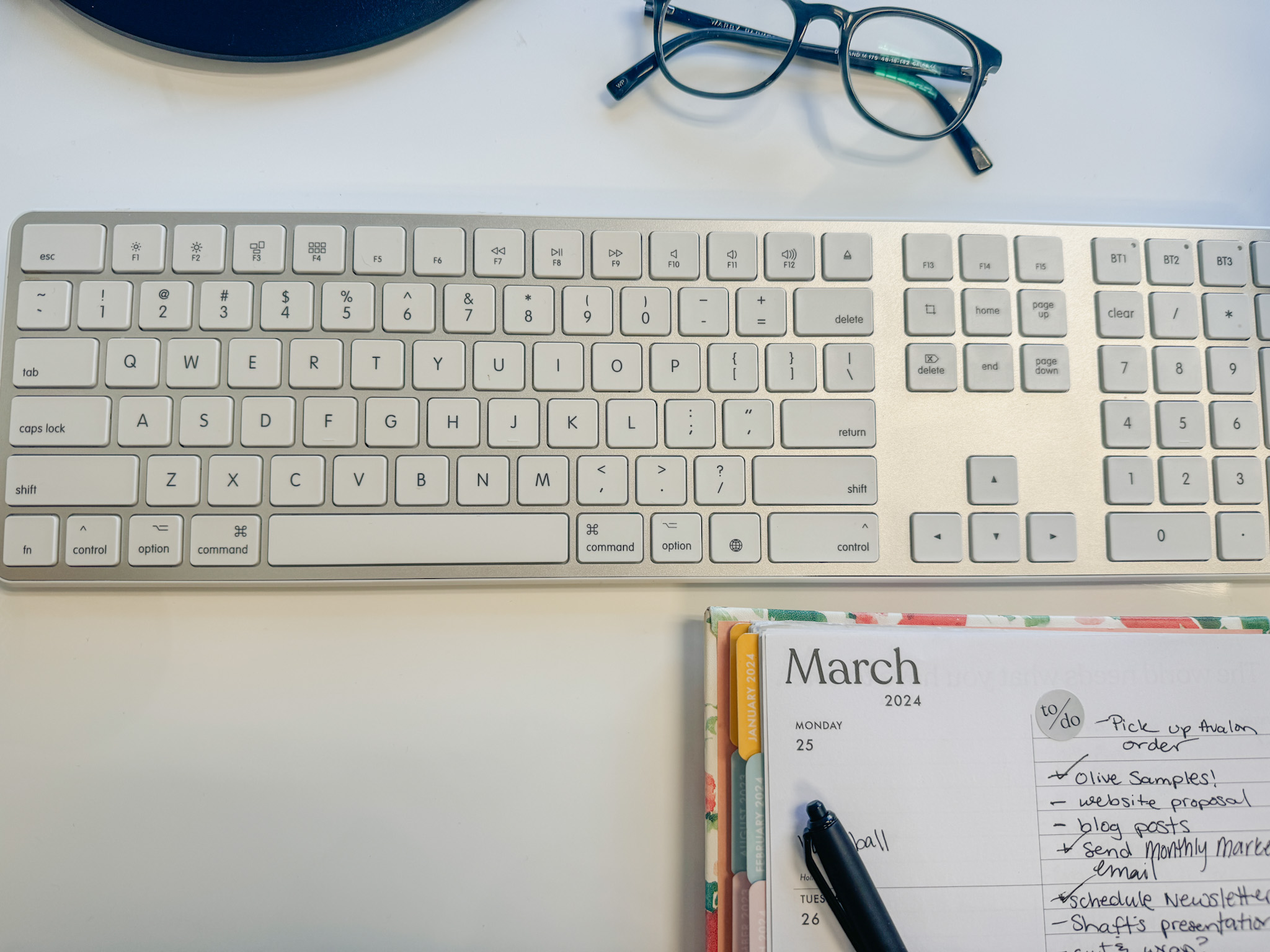 Minimal workspace with a keyboard, planner, and glasses, showing common mistakes creatives make and what not to do on Pinterest when managing content and strategy