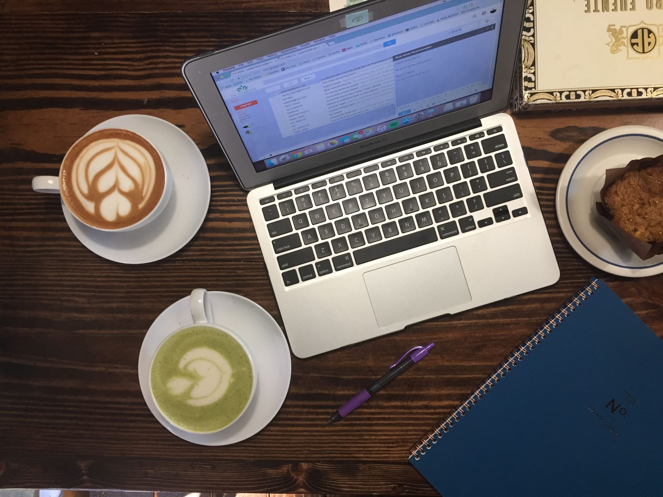 A laptop beside coffee and matcha on a Pinterest manager's desk